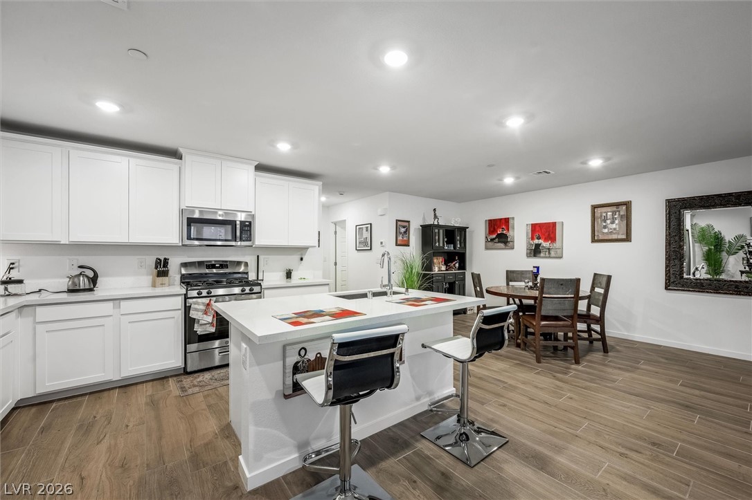 175 Hazel Heights Henderson, NV 89011 - Photo 8 of 55 Kitchen with stainless steel appliances, wood finish floors, white cabinets, a center island with sink, and recessed lighting