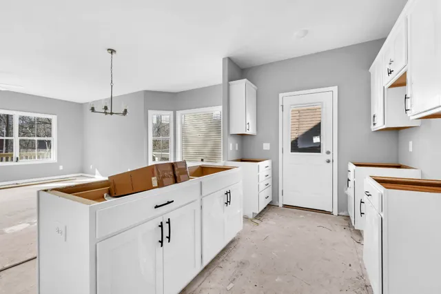 a kitchen that has a lot of cabinets in it and wooden floors