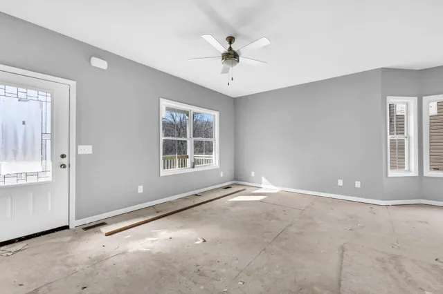 an empty room with windows and ceiling fan