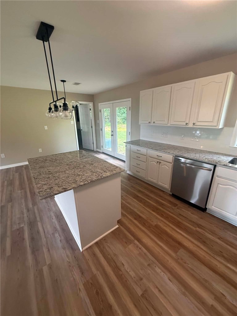 2106 Military Road Dardanelle, AR 72834 - Photo 4 of 16 Kitchen featuring wood-finish flooring, white cabinetry, a granite-top island, a tile backsplash, and a stainless steel dishwasher