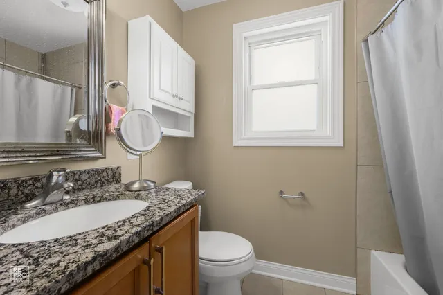 a bathroom with a granite countertop sink toilet and a mirror
