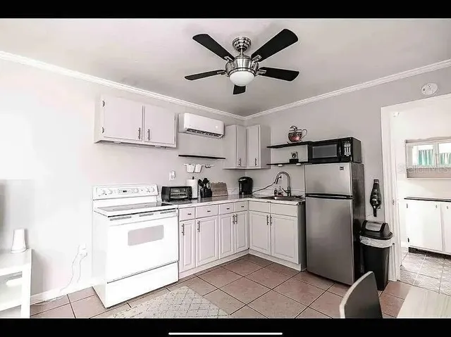 a kitchen with stainless steel appliances granite countertop a refrigerator sink stove and white cabinets