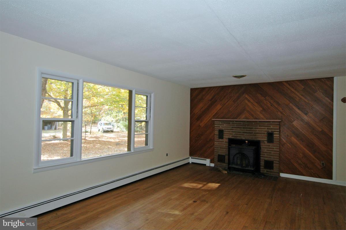 15102 Cactus Hill Road Accokeek, MD 20607 - Photo 8 of 24 an empty room with windows fireplace and wooden floor