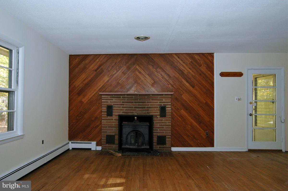 15102 Cactus Hill Road Accokeek, MD 20607 - Photo 9 of 24 a view of an empty room with wooden floor fireplace and a window