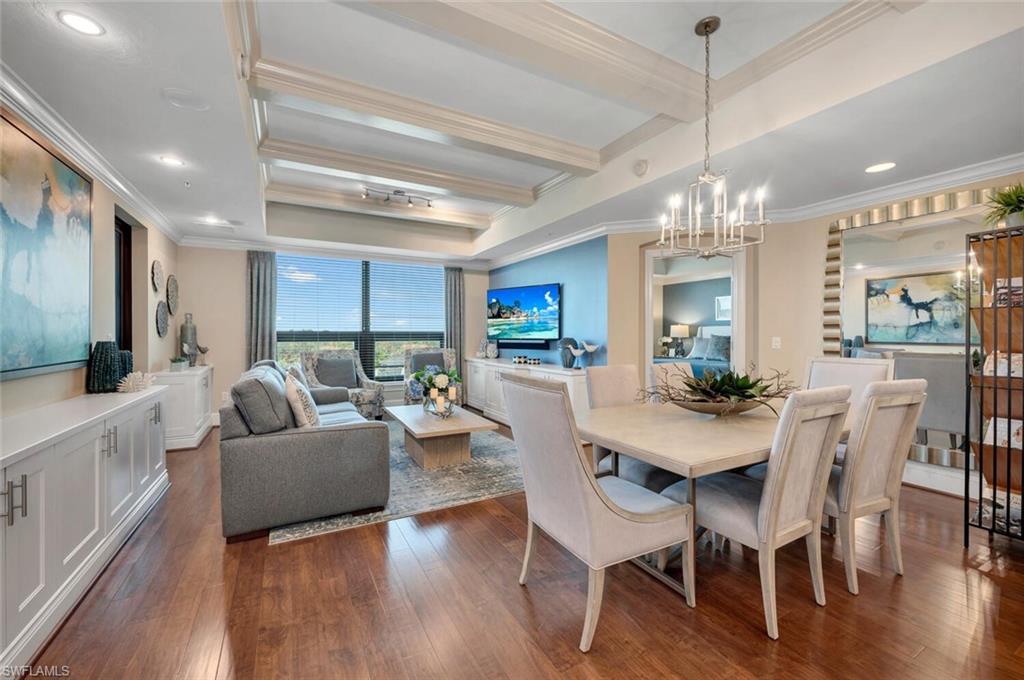 Dining space with beamed ceiling, hardwood style flooring, ornamental molding, and a chandelier