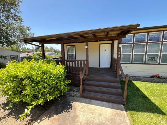 a view of a house with a small yard plants and large tree