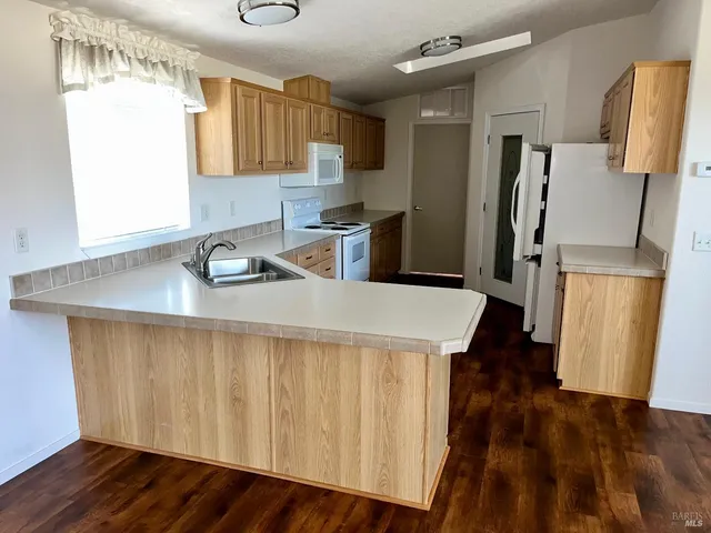 a kitchen with a refrigerator a sink and wooden floor