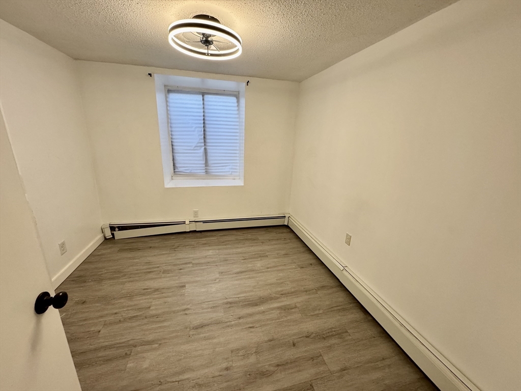 198 Allston Street, Unit 3 Boston, MA 02135 - Photo 4 of 10 an empty room with wooden floor and windows