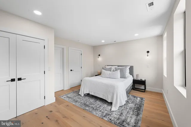a spacious bedroom with a bed and wooden floor
