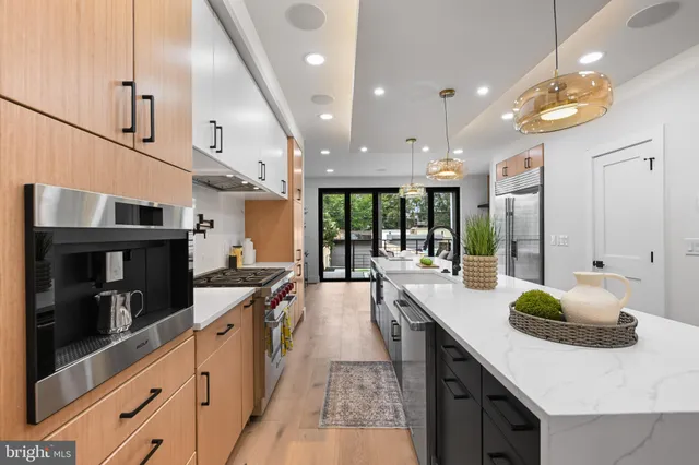 a large kitchen with stainless steel appliances a large counter top a stove and a refrigerator