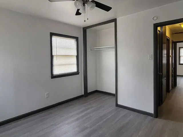 an empty room with wooden floor cabinet and windows