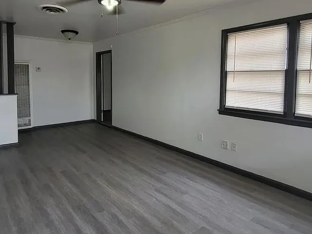 a view of an empty room with wooden floor and a window