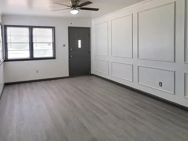 a view of an empty room with a window and wooden floor
