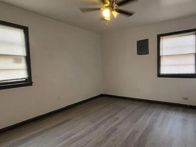 an empty room with wooden floor and windows