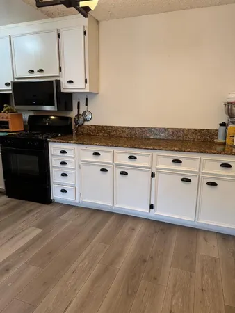 a kitchen with granite countertop white cabinets and black appliances