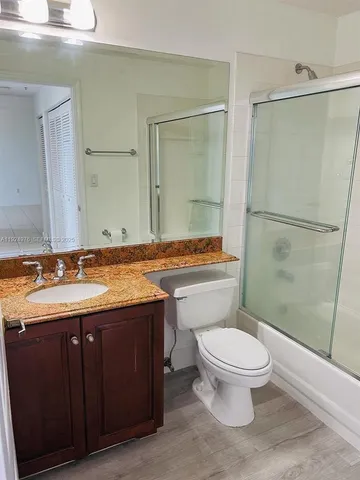 a bathroom with a granite countertop sink and mirror with bathtub