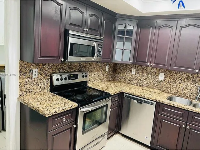 a kitchen with granite countertop stainless steel appliances a stove sink and microwave