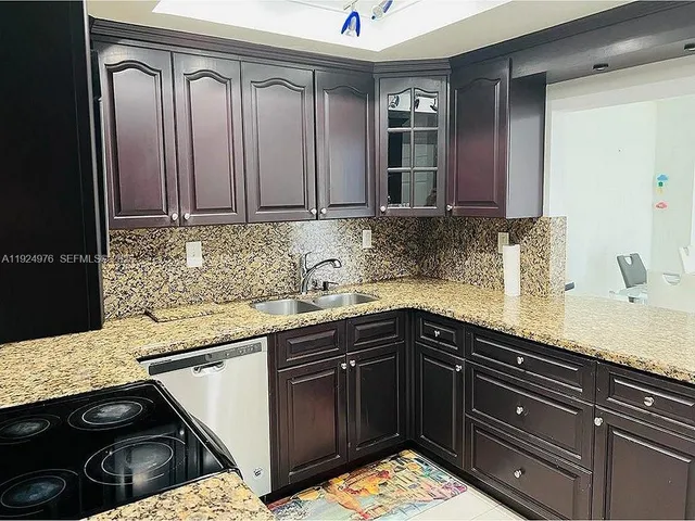 a kitchen with granite countertop a sink stainless steel appliances and cabinets