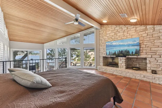 a bed sitting in a spacious bedroom next to a larger window with the balcony view