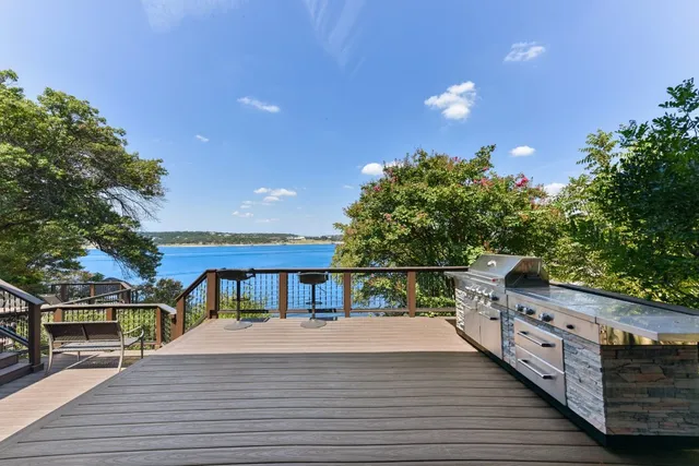 a view of a roof deck with wooden floor and fence next to a yard