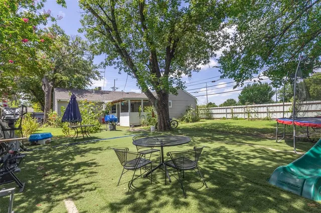 a view of a house with a big yard potted plants and large tree