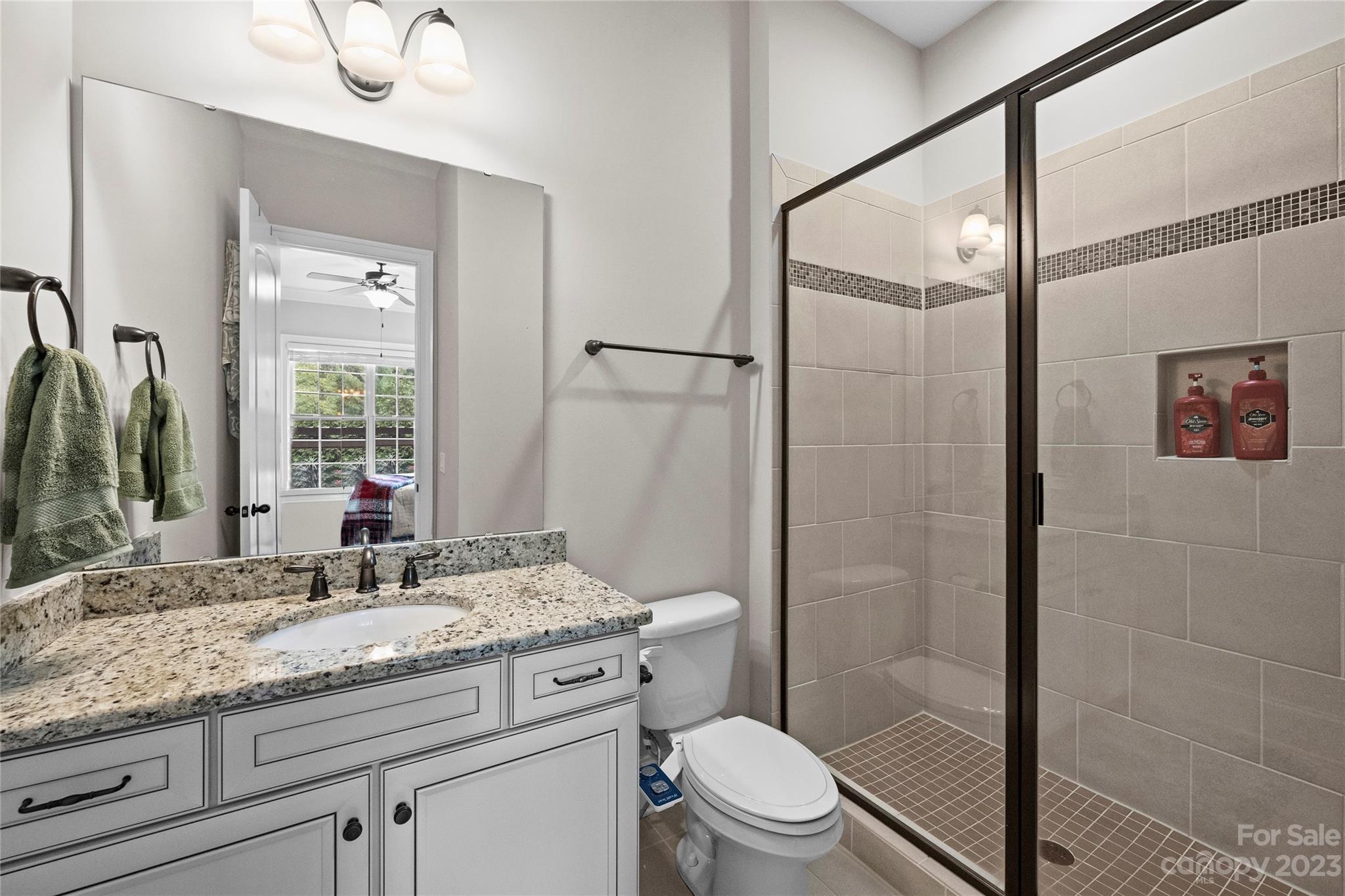 658 Zinnia Way Tega Cay, SC 29708 - Photo 13 of 32 a bathroom with a granite countertop sink a toilet and shower