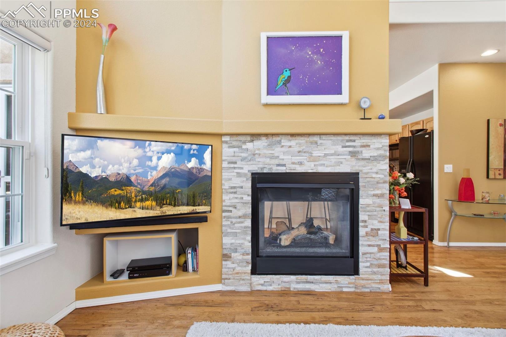 5655 Sonnet Ridge Point Colorado Springs, CO 80918 - Photo 8 of 47 Living room featuring fireplace with stone surround and hickory floors