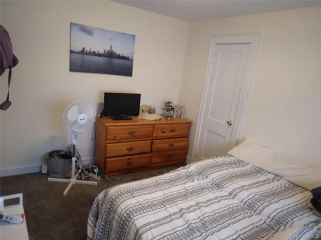 a bedroom with a bed and a flat tv screen on a dresser