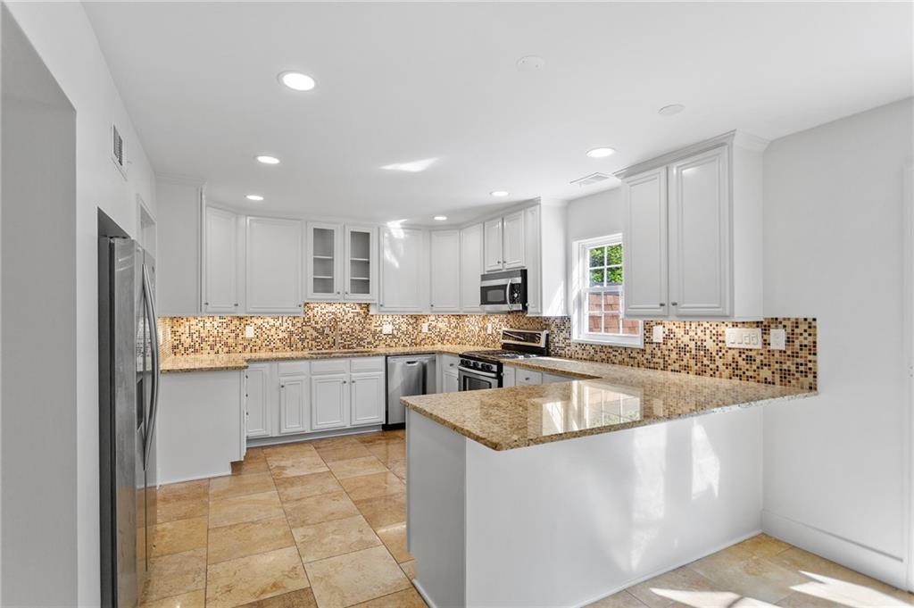 a kitchen with stainless steel appliances granite countertop a sink counter space cabinets and a large window