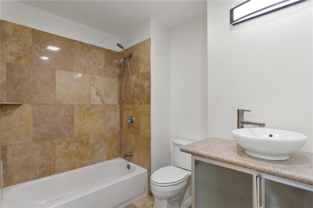 1261 Lavista Road Northeast, Unit C3 Atlanta, GA 30324 - Photo 18 of 34 a bathroom with a granite countertop sink a toilet and shower