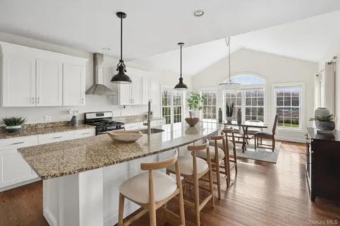 a kitchen with stainless steel appliances granite countertop a stove a kitchen island a dining table and chairs
