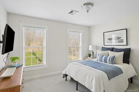 a bedroom with a bed a computer on the table and a window