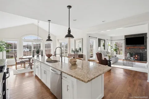 a kitchen with stainless steel appliances granite countertop a sink counter space and living room view