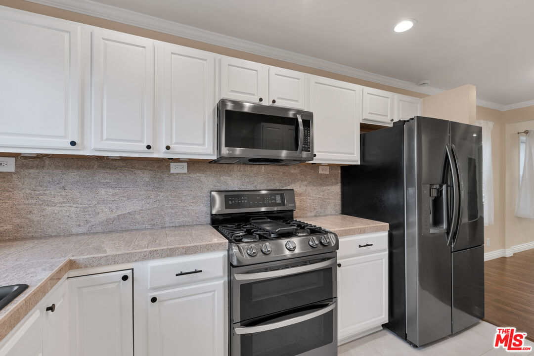 6677 West 88th Street Los Angeles, CA 90045 - Photo 7 of 23 a kitchen with stainless steel appliances white cabinets and a stove a refrigerator with a sink