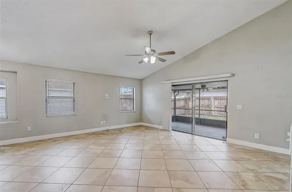 an empty room with windows and ceiling fan