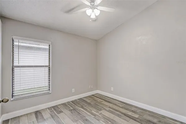 an empty room with a window and a chandelier fan
