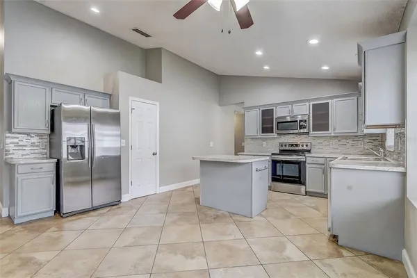 a large kitchen with a large counter top stainless steel appliances and cabinets