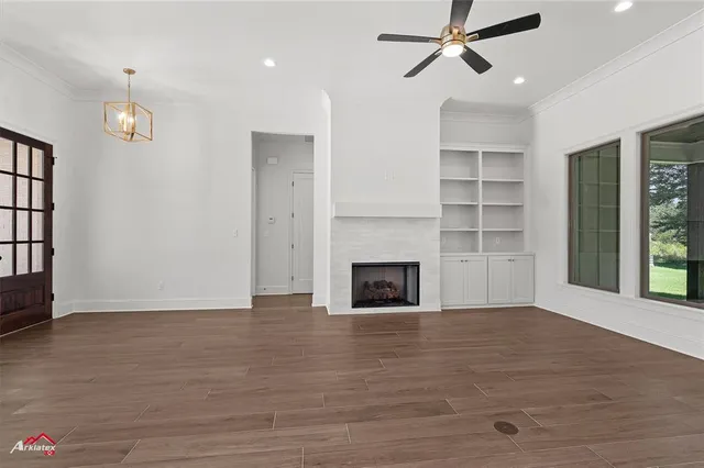 an empty room with wooden floor fireplace and windows