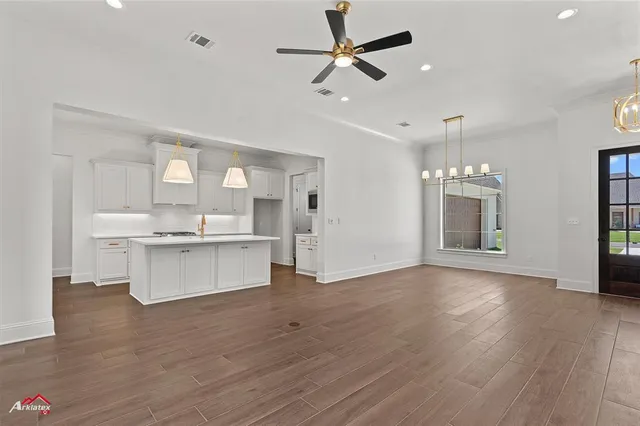 a view of an empty room with kitchen and window