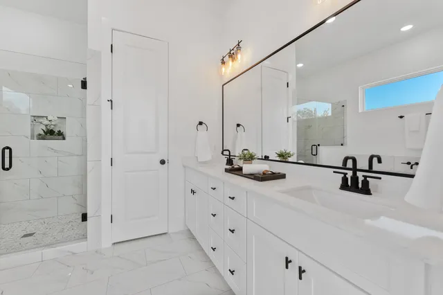a bathroom with double vanity sink a mirror and shower
