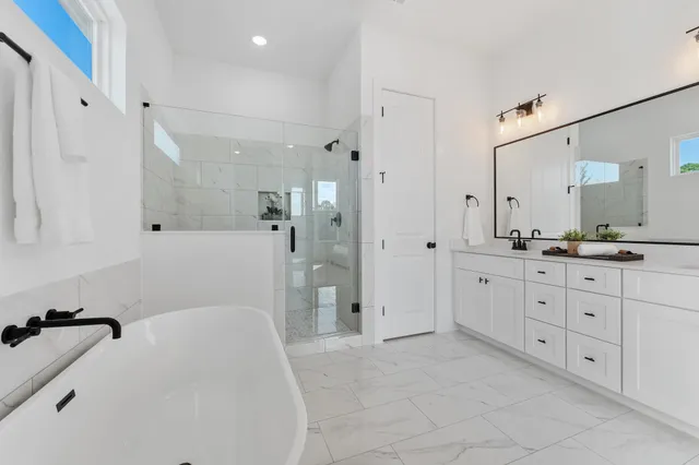 a spacious bathroom with a granite countertop sink a mirror a bathtub and shower