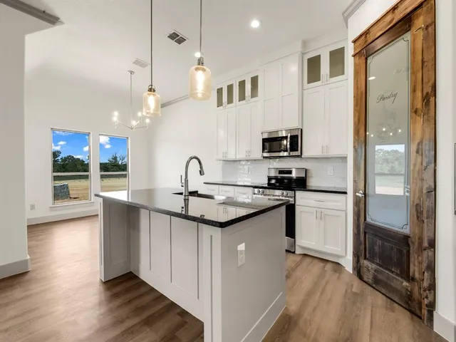 a kitchen with stainless steel appliances granite countertop a sink a stove a refrigerator and a microwave