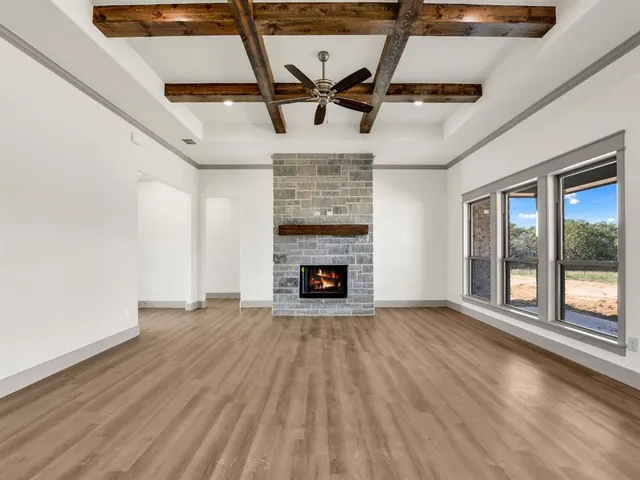 a view of an empty room with wooden floor fireplace and a window