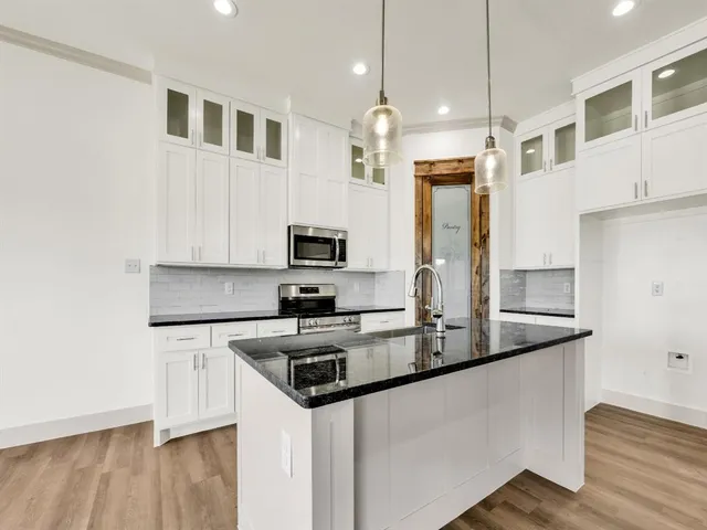 a kitchen with stainless steel appliances granite countertop a sink a stove and refrigerator
