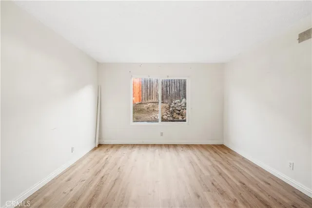 an empty room with wooden floor and window