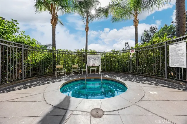 a front view of a house with fountain plants and large tree