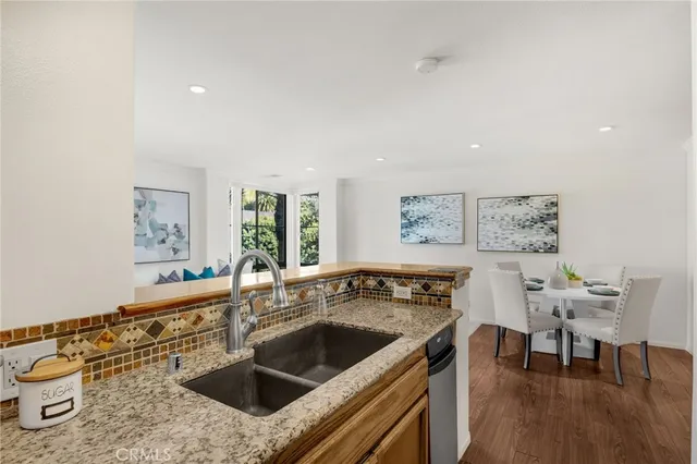 a kitchen with a stove a sink and a refrigerator with wooden floor