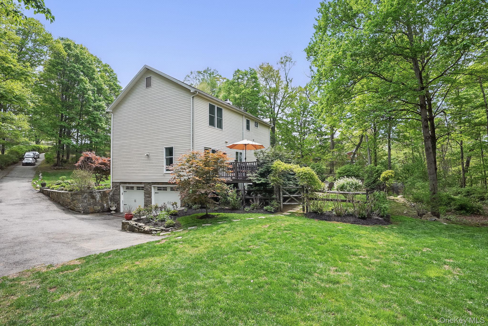304 Church Road Putnam Valley, NY 10579 - Photo 39 of 50 View of property exterior featuring an attached garage, a lawn, a wooden deck, and driveway