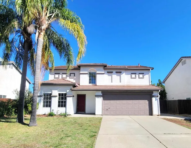 a view of a white building with a large tree