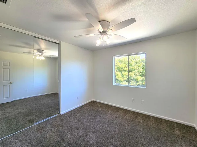 an empty room with a window and a fan